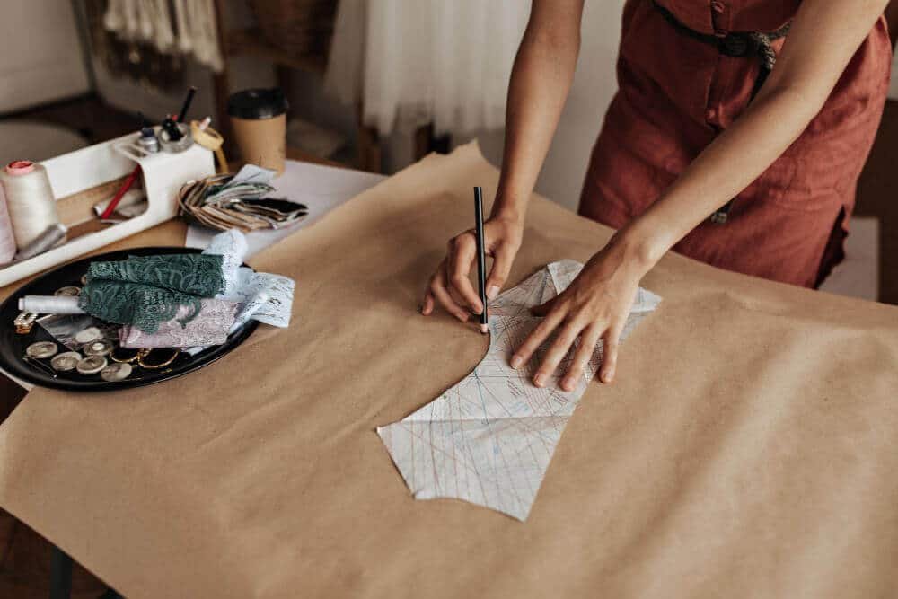 tanned-woman-linen-red-dress-draws-cloth-pattern-craft-paper-fashion-designer-creates-garment-sample-office